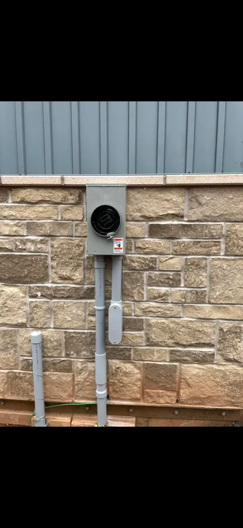 New meter base and conduit installed on a stone foundation